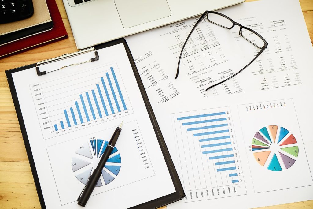 pages of charts with pen and glasses - What Does ROI Stand For: Arcane Marketing